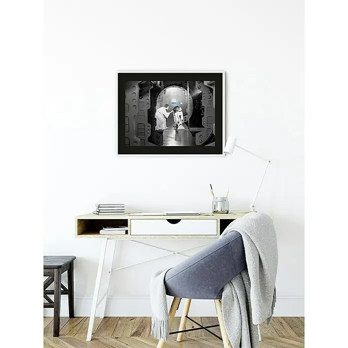 Komar Star Wars Poster Leia R2D2 Upload - Star Wars, B x H: 70 x 50 cm - Gerahmtes Schwarzweißfoto mit Star Wars-Motiv, das über einem Schreibtisch an einer weißen Wand hängt.
