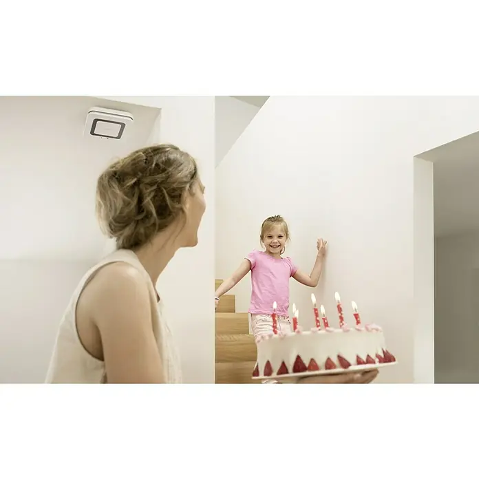 Bosch Smart Home Rauchwarnmelder Twinguard - Batterielaufzeit: 2 Jahre, 41 x 138 x 138 mm - Szene mit einer Mutter und einem Kind mit einer Geburtstagstorte. An der Decke ist ein Bosch Smart Home Rauchmelder installiert.