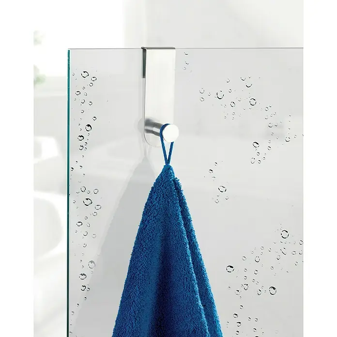 Wenko Toallero de gancho Celano - Acero inoxidable, Cabina de ducha - Una toalla azul colgada de un moderno gancho de puerta plateado en una mampara de ducha de cristal con gotas de agua.