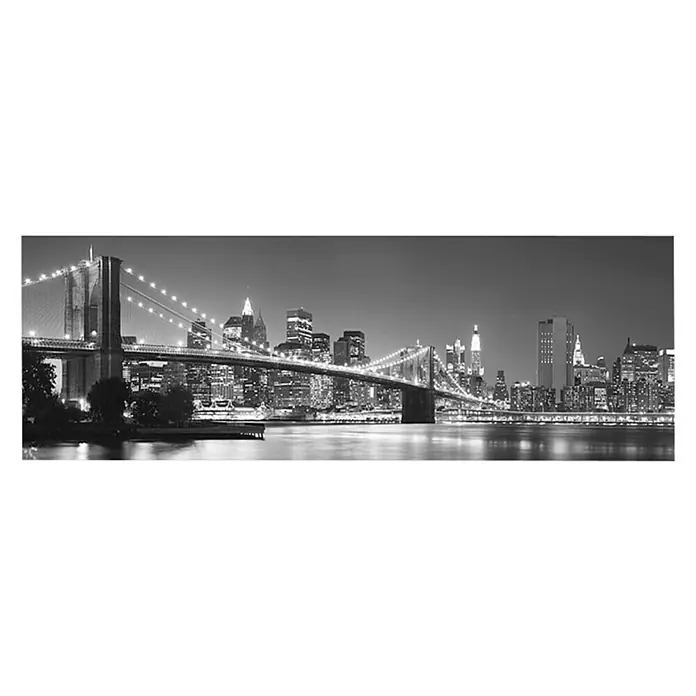 Leinwandbild - Brooklyn Bridge At Night, B x H: 145 x 45 cm - Schwarz-Weiß-Foto der Brooklyn Bridge und der New Yorker Skyline bei Nacht. Beleuchtete Brücke und funkelnde Stadtlichter reflektieren sich im Wasser.