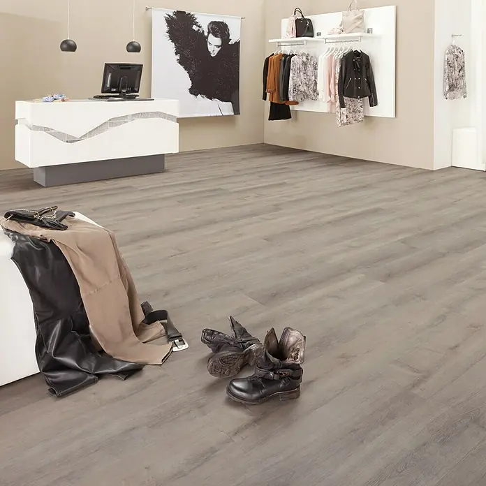 b!design Vinylboden Maxi - Sherwood Eiche, Landhausdiele, 1.210 x 220 x 4,2 mm - Elegantes Interieur eines Modegeschäfts mit Fokus auf hochwertigen Schuhen und Bekleidung auf einem stilvollen Boden.