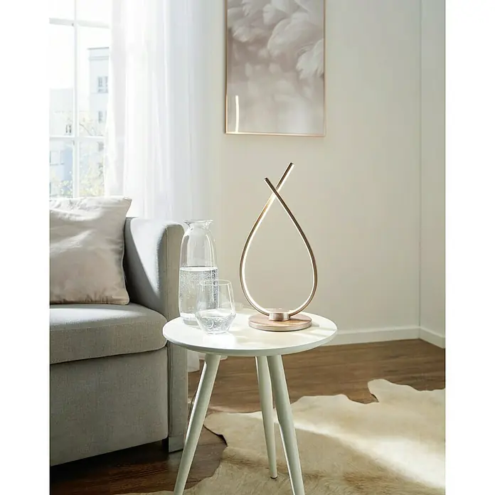 Eglo Palozza Lámpara de sobremesa LED Palozza - 14 W, L x An x Al: 15 x 18,5 x 38 cm, Rosa dorado, Blanco cálido - Lámpara de mesa moderna de metal con forma de lágrima con iluminación LED sobre una mesa auxiliar, al lado de un sofá con cojín y un jarrón con agua.