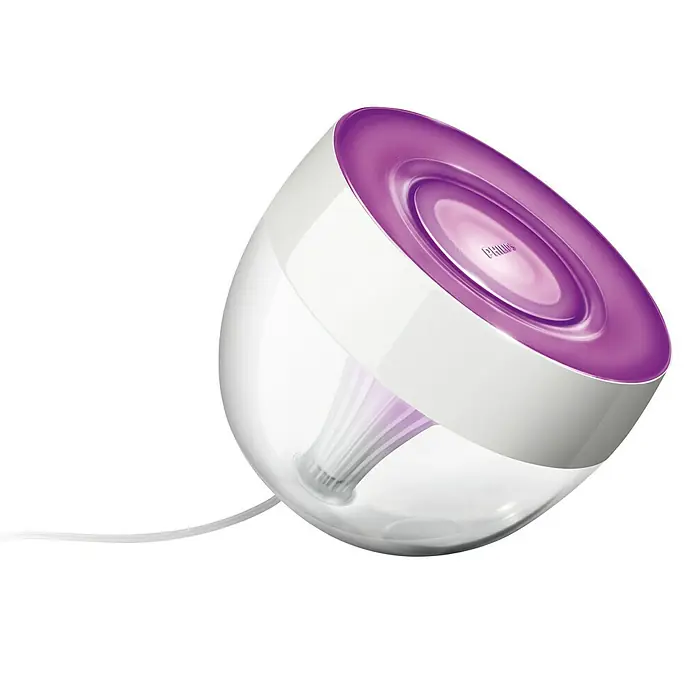 Philips Hue LED-Tischleuchte Iris - Weiß/Transparent, Höhe: 19,4 cm - Nahaufnahme einer Philips Hue Lampe, die violettes Licht ausstrahlt, mit klarem und weißem Gehäuse auf schwarzem Hintergrund.