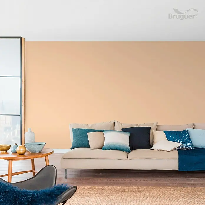 Bruguer Colores del Mundo Tester de pintura - Egipto ocre intermedio, Mate, 30 ml - Salón con pintura de pared beige de Bruguer, un sofá beige con cojines y una mesa de madera con cuencos decorativos.