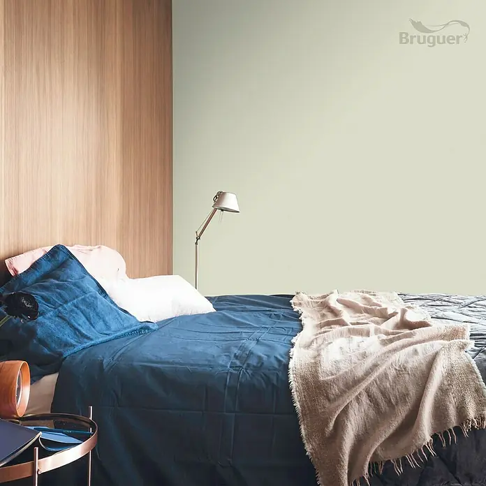 Bruguer Colores del Mundo Tester de pintura - Amazonas verde suave, Mate, 30 ml - Dormitorio con una cama con ropa de cama azul y una manta beige, sobre una pared verde claro, destacando la pintura Bruguer.