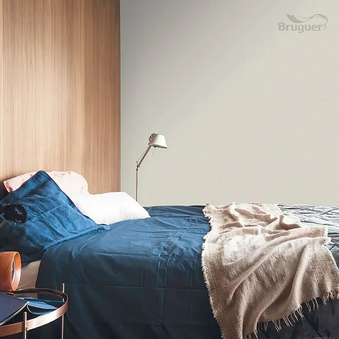 Bruguer Colores del Mundo Tester de pintura - Nepal beige suave, Mate, 30 ml - Acogedora habitación con pared de madera y cama con ropa de cama azul y manta beige. La pared está pintada en un tono neutro.