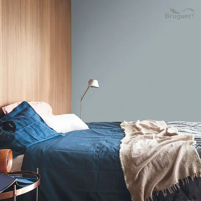 Bruguer Colores del Mundo Tester de pintura - Escandinavia gris intermedio, Mate, 30 ml - Luminoso dormitorio con una cómoda cama cubierta de azul, completa con almohadas y una manta para una sensación acogedora.