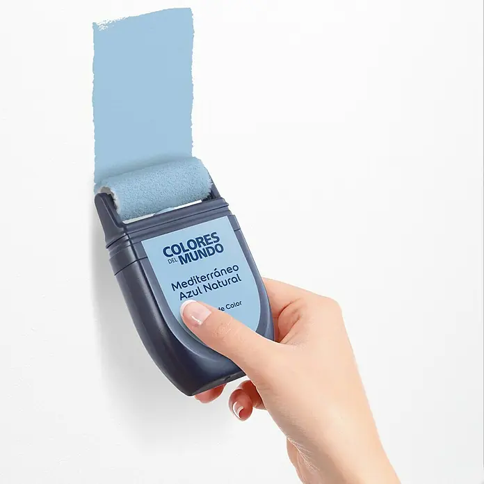 Bruguer Colores del Mundo Tester de pintura - Mediterráneo azul natural, Mate, 30 ml - Primer plano de un rodillo aplicador de pintura con el tono "Mediterráneo Azul Natural" de Colores del Mundo, aplicando una muestra de color azul claro a una pared blanca.