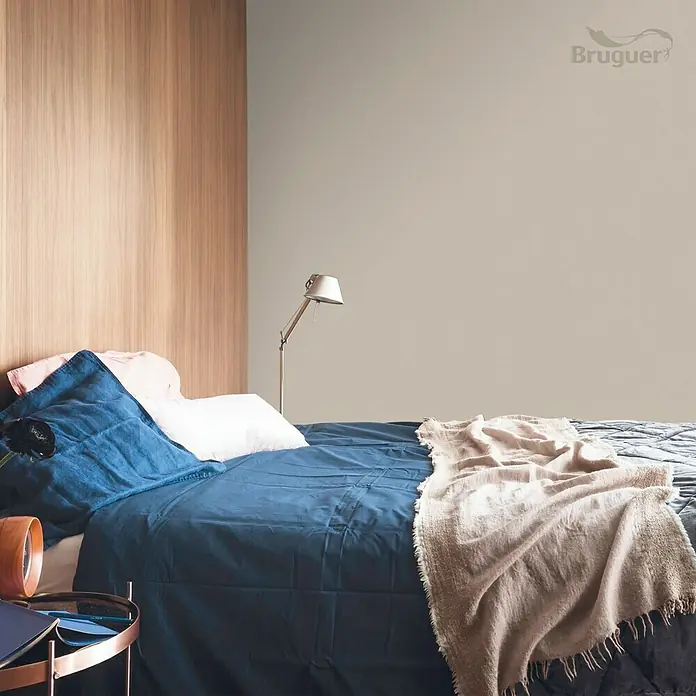 Bruguer Colores del Mundo Tester de pintura - Nepal beige natural, Mate, 30 ml - Dormitorio luminoso con ropa de cama azul, pared de madera y lámpara. Espacio acogedor con colores suaves y ambiente cómodo.