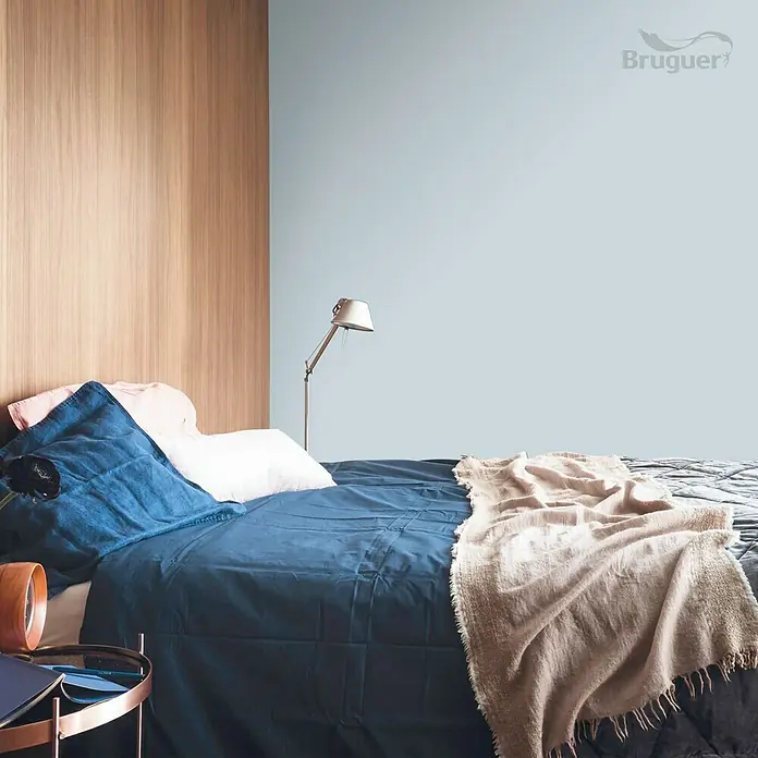 Bruguer Colores del Mundo Tester de pintura - Mediterráneo azul suave, Mate, 30 ml - Dormitorio con cama con ropa de cama azul, almohadas y una manta marrón claro delante de una pared pintada con Bruguer.