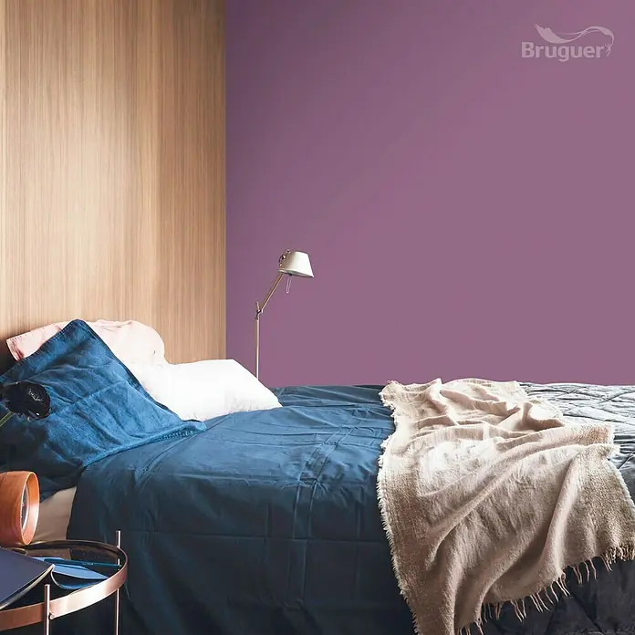 Bruguer Colores del Mundo Tester de pintura - Japón violeta natural, Mate, 30 ml - Dormitorio con pintura de pared morada de Bruguer, ropa de cama azul y detalles de madera para un ambiente moderno y acogedor.