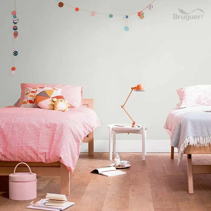 Bruguer Ultra Resist Tester de pintura - Gris neutro, Mate, 30 ml - Habitación infantil luminosa con dos camas y lámpara naranja. La pared está pintada en un suave tono verde, creando un ambiente relajante.
