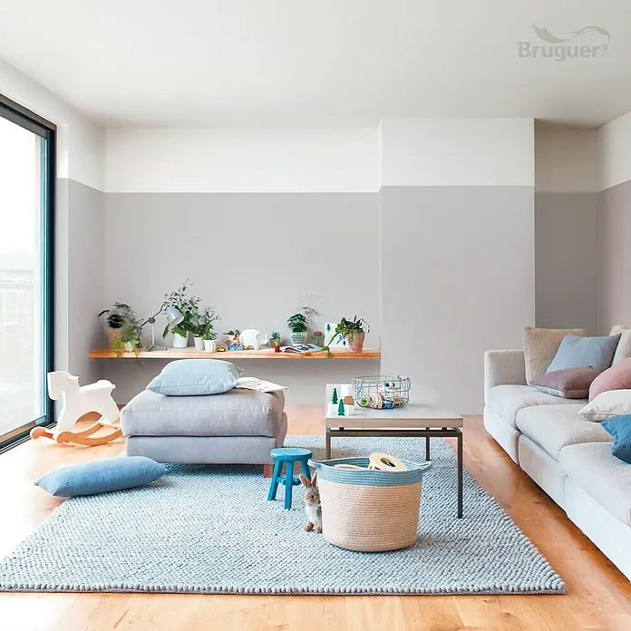 Bruguer Ultra Resist Tester de pintura - Gris clásico, Mate, 30 ml - Alfombra gris claro con cesto de mimbre, taburete azul y otomana en una habitación luminosa. Decoración elegante y apta para niños.