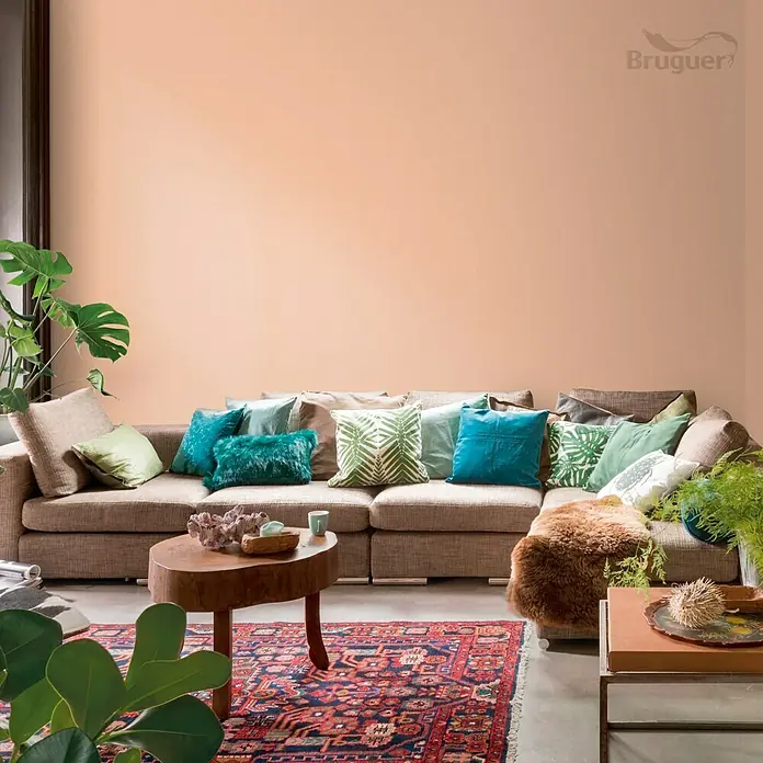 Bruguer Colores del Mundo Tester de pintura - India melocotón suave, Mate, 30 ml - Salón con un sofá grande, cojines de colores y una mesa baja de madera, creando un ambiente acogedor y agradable.