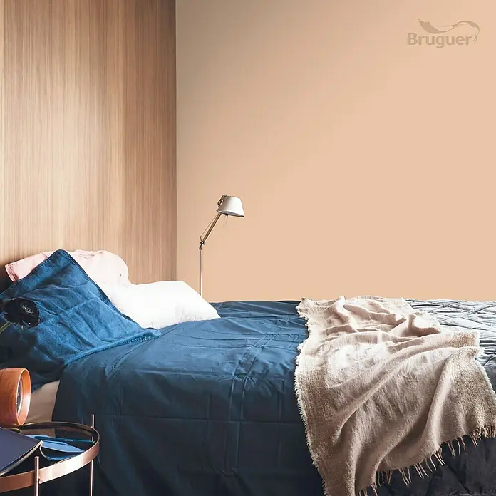 Bruguer Colores del Mundo Tester de pintura - India melocotón suave, Mate, 30 ml - Elegante dormitorio con ropa de cama azul y beige, pared color melocotón. Logotipo de Bruguer en la esquina, el producto es la pintura de pared.