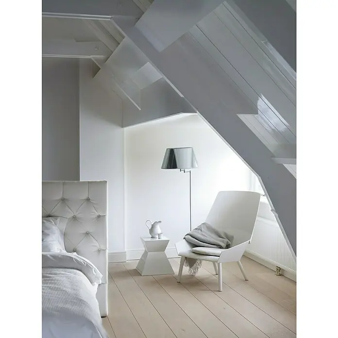 Bruguer Colores del Mundo Tester de pintura - Alaska blanco luminoso, Mate, 30 ml - Elegante interior blanco con una silla moderna, una lámpara de pie elegante y una mesita de noche. El diseño luminoso irradia calma y confort.