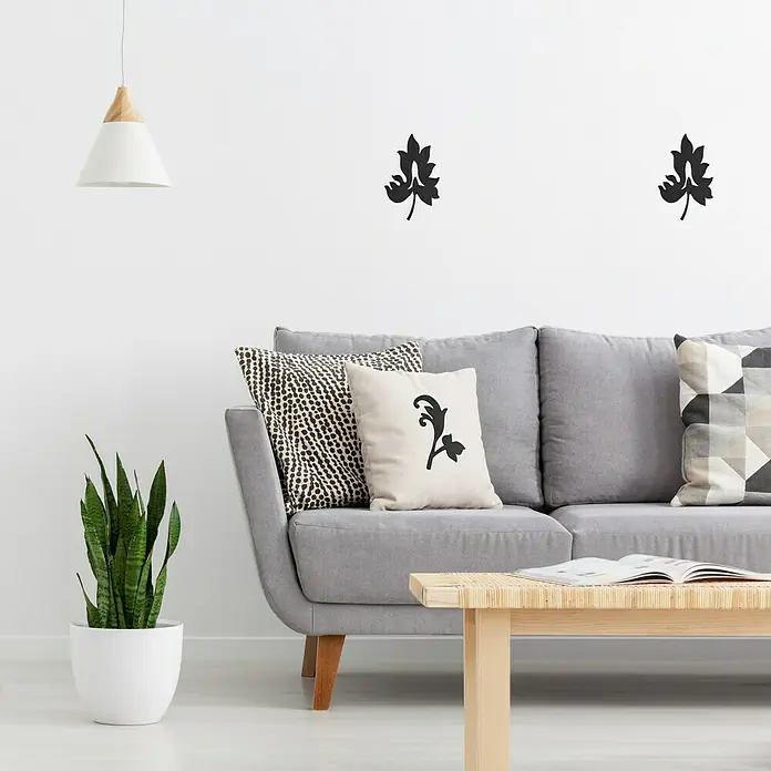 Vinilo de pared Barroco 3 - Negro, Textil - Una elegante escena de sala de estar con un sofá gris, cojines decorativos, una mesa de madera y una planta en maceta en una maceta blanca.
