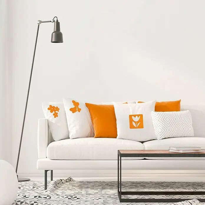 Vinilo de pared Flores - Naranja, Textil - Acogedora sala de estar con un sofá blanco, decorado con cojines decorativos en blanco y naranja que añaden un toque de color.