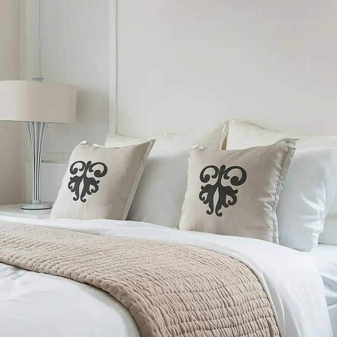 Vinilo de pared barroco 1 - Negro, Textil - Esta imagen muestra una cama elegante con cojines decorativos y una colcha, ideal para un ambiente de dormitorio acogedor.