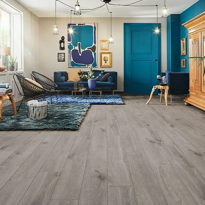 LOGOCLIC Laminatmuster Aquaprotect Moonlight Oak - 290 x 200 x 8 mm, Landhausdiele - Modernes Wohnzimmer mit grauem Holzboden, blauem Sofa und Teppich. Stilvolle Einrichtung mit eleganten Lampen.