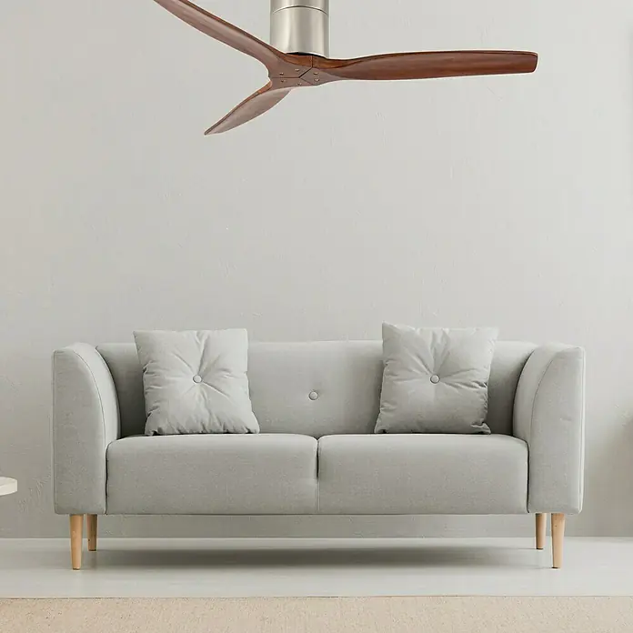 Arte confort Ventilador de techo Viena - Roble, 132 cm, 23 W - Primer plano de un moderno ventilador de techo con tres aspas de madera y fijación plateada sobre un sofá gris.
