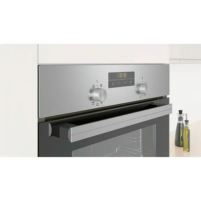 Balay Horno empotrado 3HB2031X0 - 66 l, Número de tipos de calentamiento: 7 ud. - Primer plano de un horno empotrable moderno de acero inoxidable con pantalla digital y mandos giratorios, integrado en una cocina blanca.