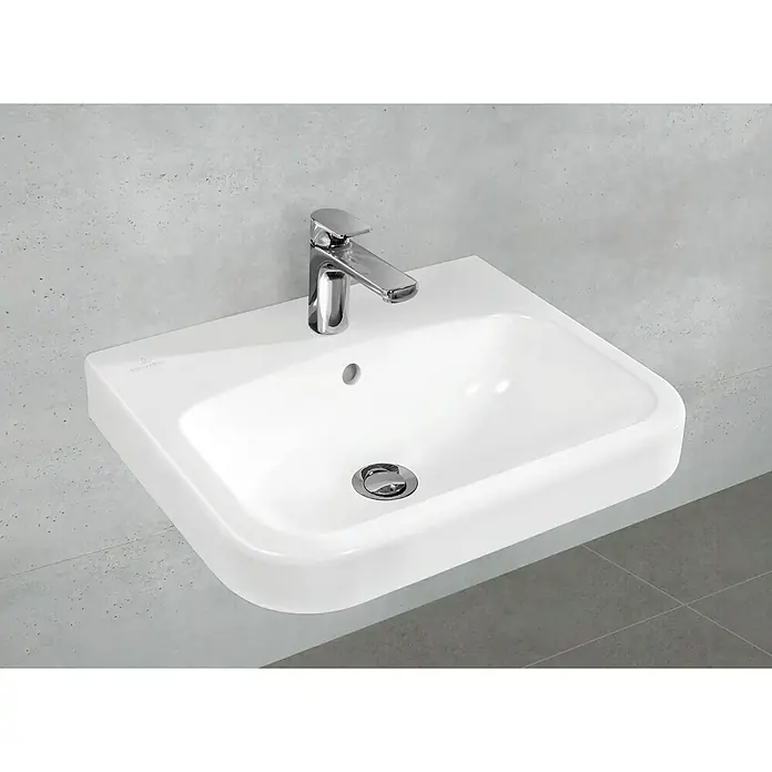 Villeroy & Boch Architectura Waschtisch 1 - 55 x 47 cm, Ohne Spezialglasur, Hahnloch: Mitte, Mit Überlauf, Weiß - Ansicht eines weißen Villeroy & Boch Waschbeckens mit Armatur vor einer grauen Wand.
