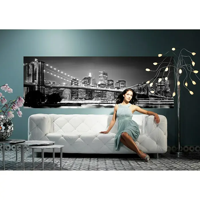Komar Into Illusions Fototapete Brooklyn Bridge - 2 -tlg., B x H: 184 x 248 cm, Vlies - Elegante Frau auf einem weißen Sofa vor einer New Yorker Skyline, stilvolle Beleuchtung und Dekoration schaffen eine moderne Atmosphäre.