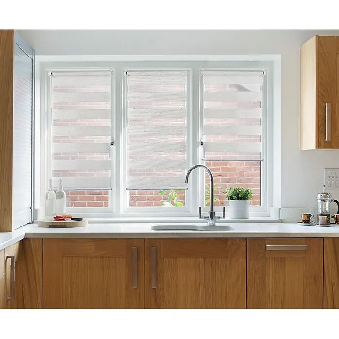 Estor noche y día Clip&Fix - An x Al: 60 x 180 cm, Lino - Una ventana de cocina con modernas persianas enrollables blancas, parcialmente levantadas para revelar una vista del edificio de ladrillo al aire libre.