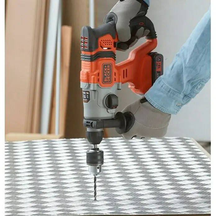 Black+Decker Martillo combinado de batería BCD900E2K - 18 V, 2 baterías, 1,2 J - Taladro percutor Black+Decker, sujetado por una mano con guante de trabajo, perforando un patrón de cuadros.