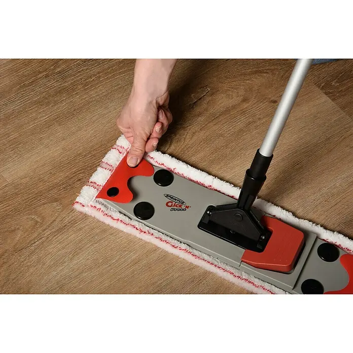 Sprintus Bodenwisch-Set Click N Press + Staubmop - 12 l, 5 -tlg., Materialzusammensetzung Bezug: 80 % Mikrofaser, 20 % weiche Abrasivborsten - Das Bild zeigt einen Sprintus Click 'n' Press Bodenwischer in Aktion, der auf einem Holzboden verwendet wird. Die Hand fixiert das Wischtuch.