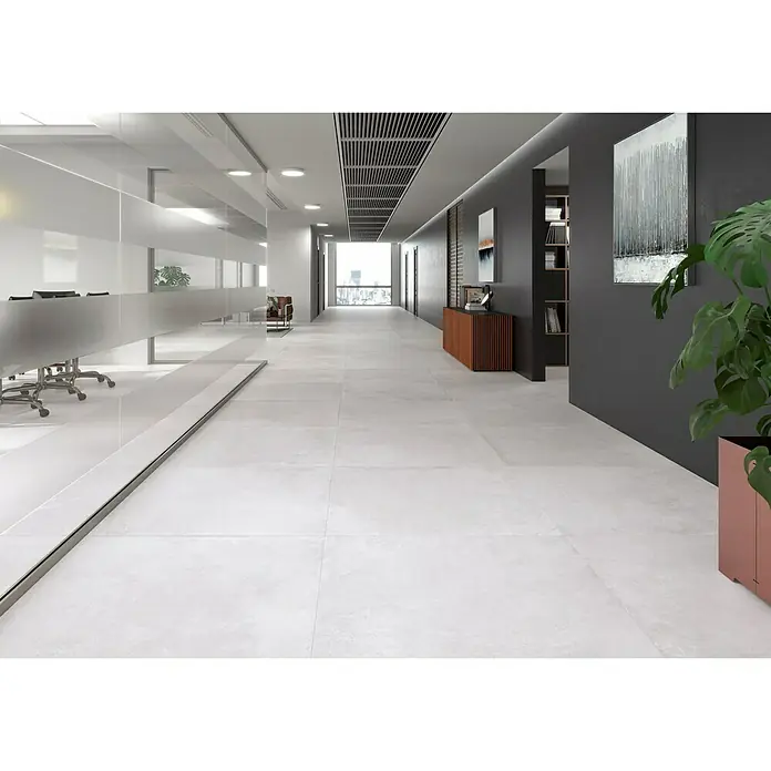 BHS Showroom Pavimento porcelánico Lorraine - 60 x 60 cm, Blanco, Rectificado - Pasillo de oficina con baldosas de color gris claro. Las baldosas crean un ambiente moderno y elegante en el espacio.\n