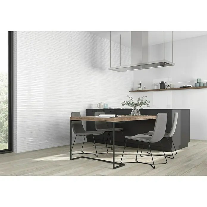 BHS Showroom Pavimento porcelánico Arhus - 120 x 23 cm, Gris, Rectificado - Diseño de cocina moderno con azulejos blancos ondulados en la pared, mesa de comedor y sillas grises, suelos de madera clara y campana extractora minimalista.