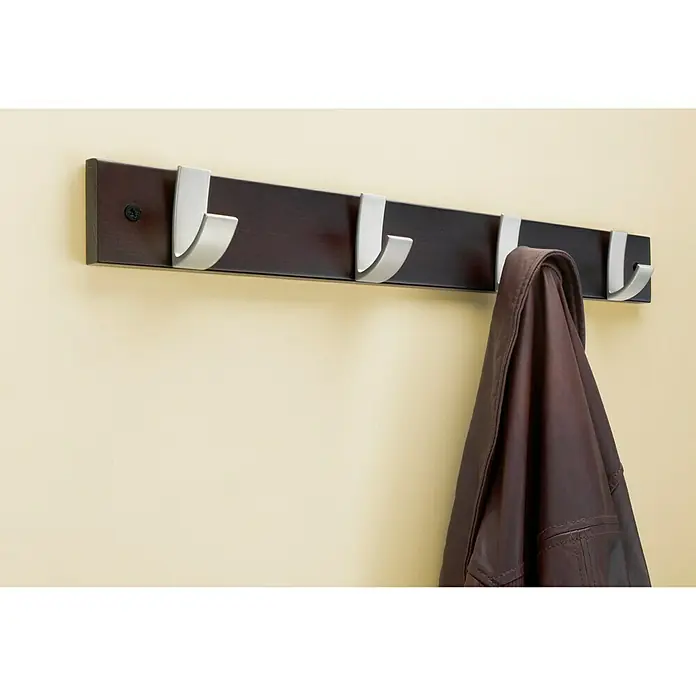 Inofix Perchero 3704 - L x An x Al: 490 x 60 x 60 mm, Madera, Roble/Negro - Un perchero de pared marrón con ganchos plateados, con una chaqueta colgada, contra una pared beige.