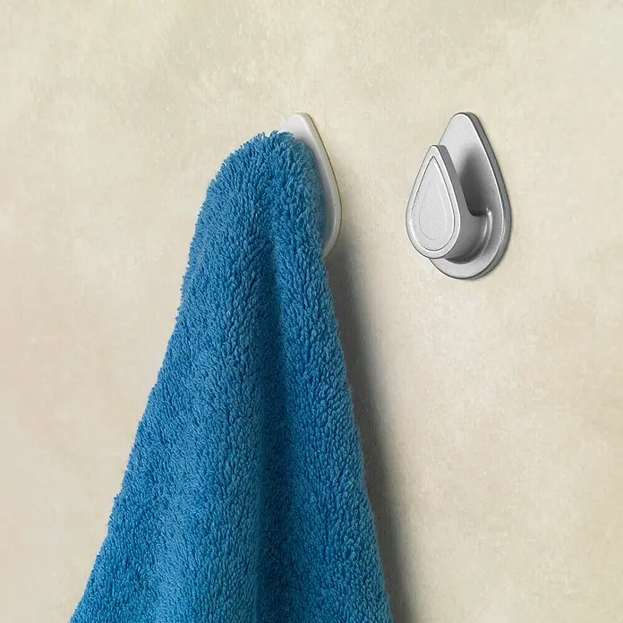 Inofix Colgador adhesivo 2193-2 - Blanco - Una toalla azul cuelga de un gancho blanco con forma de lágrima en una pared, con otro gancho cerca.