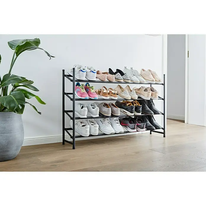 Schuhregal Loft - L x B x H: 23 x 116 x 68 cm, Schwarz - Schuhregal mit vier Ebenen voll mit verschiedenen Schuhen und Stiefeln, neben einer Topfpflanze an einer weißen Wand.