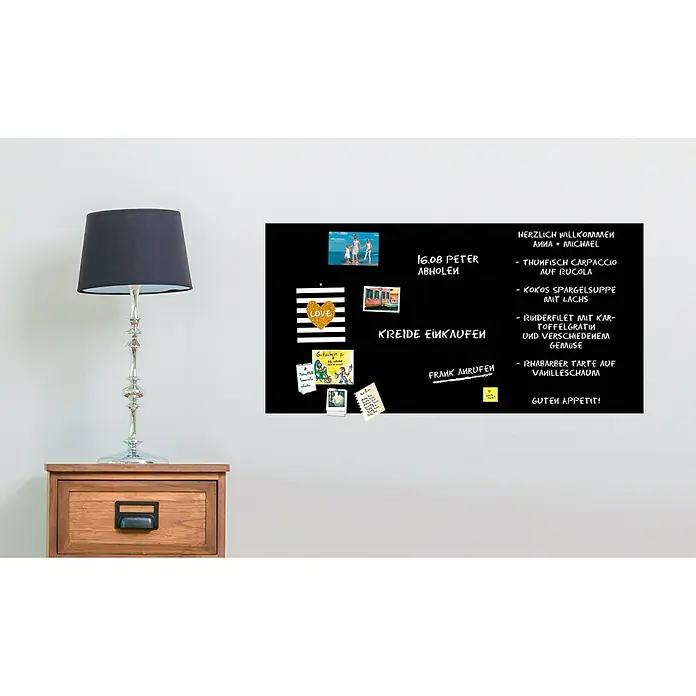 Magnetische Tafelfolie - Schwarz, 100 x 50 cm, Inkl. 3 Magnete und 3 Stück Kreide - Schwarze Magnettafel mit Notizen und Fotos an einer Wand über einem Nachttisch mit Lampe.