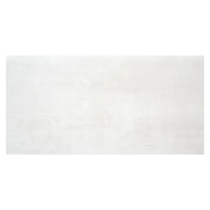 BHS Showroom Pavimento porcelánico Steel - 60 x 120 cm, Blanco, Rectificado - Pared de hormigón gris con manchas ligeramente texturizadas, creando un fondo moderno e industrial.