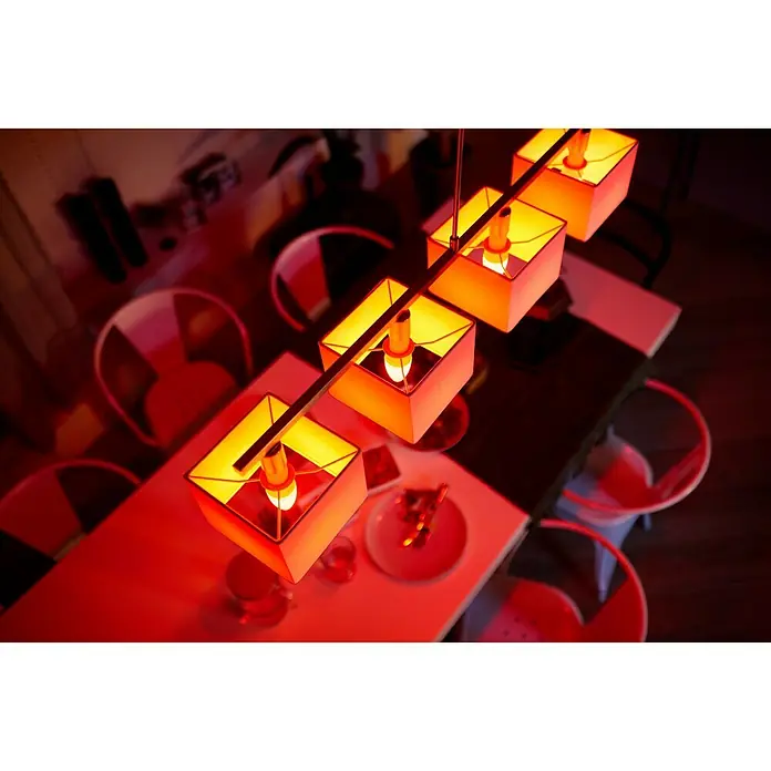 Philips Hue Smart-LED-Lampe White & Color Ambiance - E14, Dimmbar, RGBW, 470 lm, 5,3 W - Diese Aufnahme zeigt eine moderne Pendelleuchte mit vier Lampenschirmen über einem Esstisch, die ein warmes, einladendes Licht verbreitet.