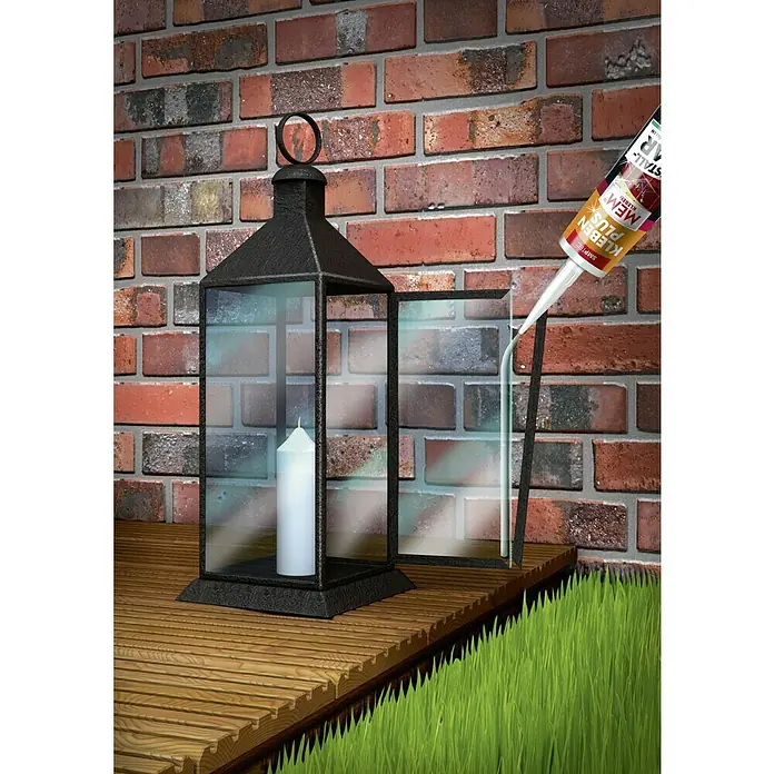 MEM Montagekleber ALLGROUND 3in1 - Metall, 305 g - Nahaufnahme einer MEM Kleben Plus Kartusche, die Glas in einer Laterne befestigt, vor einem Backsteinhintergrund auf Holz und Gras.
