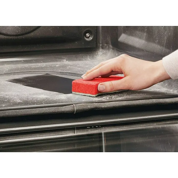 AEG Horno empotrado BPE53512YM - Número de tipos de calentamiento: 10 ud., Volumen horno: 71 l - Una mano limpia el interior de un horno con una esponja roja. La esponja elimina sin esfuerzo la suciedad incrustada.