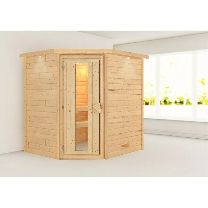 Karibu Massivholzsauna Mia - L x B x H: 184 x 224 x 202 cm, Materialspezifizierung Tür: Massivholz, Inklusive Ofenschutzgitter, Mit Dachkranz und Beleuchtung - Eine Ecke der Holzsauna mit Glastür in einem hellen Raum. Die Sauna hat eine warme, einladende Ausstrahlung.