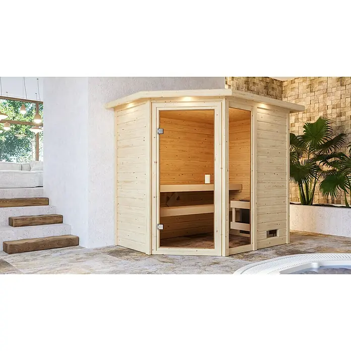 Karibu Massivholzsauna Jada - L x B x H: 160 x 224 x 191 cm, Ohne Ofen, Mit Dachkranz und Beleuchtung - Eine luxuriöse Holzsauna mit Glasfront, eingebaut in einem modernen Interieur mit Holzelementen und Pflanzen.