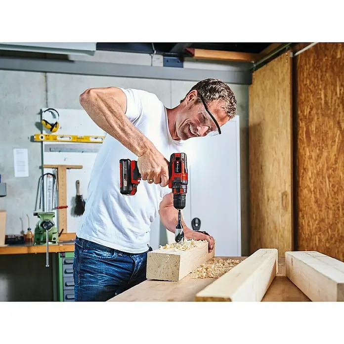 Einhell Power X-Change 18V Akku-Bohrschrauber TC-CD 18/35 - 18 V, 1 Akku, 1,5 Ah, 35 Nm - Ein Mann bohrt mit einer Einhell Akku-Bohrmaschine ein Loch in ein Holzbrett. Er trägt dabei eine Schutzbrille und ist konzentriert bei der Arbeit.