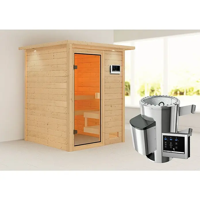 Karibu Massivholzsauna Sandra - L x B x H: 159 x 173 x 191 cm, Mit Dachkranz und Beleuchtung, 3,6 kW Saunaofen mit multifunktionaler Steuerung - Das Bild zeigt eine Sauna mit Heizgerät. Die Sauna ist aus hellem Holz und hat eine Glastür, daneben befindet sich ein silbernes Heizgerät.