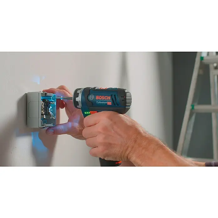 Bosch Professional Akku-Bohrschrauber GSR 12V-15 FC - 12 V, Ohne Akku, 30 Nm - Ein blauer Bosch Professional Akku-Bohrschrauber wird benutzt, um eine graue Steckdose an einer weißen Wand zu befestigen, während eine Leiter im Hintergrund steht.