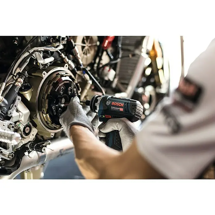 Bosch Professional Taladro atornillador de batería GSR 12V-15 FC - 12 V, 2 baterías, 2 Ah, 30 Nm, 11 pzs. - Un trabajador utiliza un taladro inalámbrico Bosch para trabajar en una motocicleta.