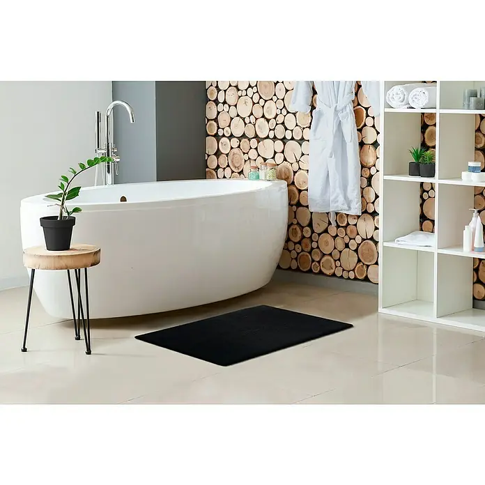 Badteppich Happy - 60 x 40 cm, Naturmaterialien, Schwarz - Ein modernes Badezimmer mit einer freistehenden Badewanne, einem Holzhocker mit Pflanze und einem schwarzen Badteppich.