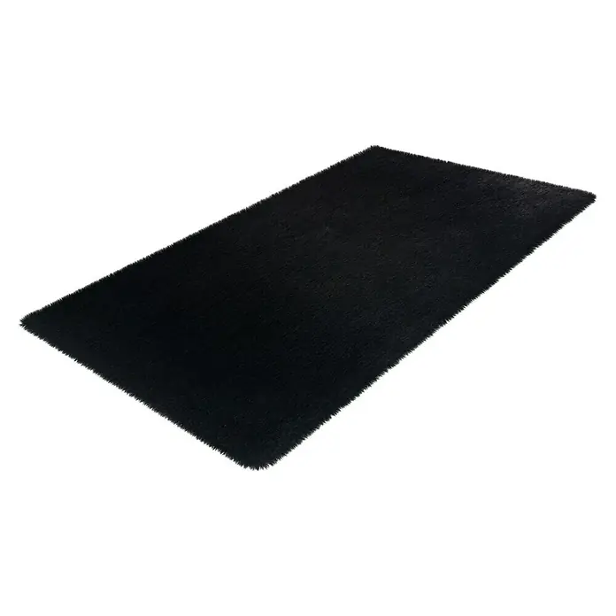 Badteppich Happy - 50 x 90 cm, Schwarz, 100% Polyester - Ein rechteckiger, schwarzer Teppich mit hochflorigem Flor ist schräg auf einer weißen Fläche platziert und verleiht jedem Raum eine elegante Note.