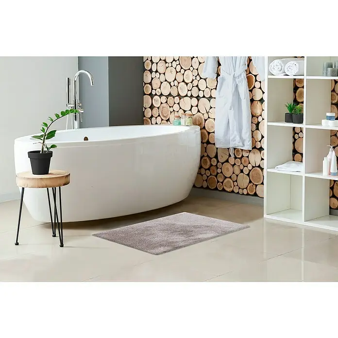 Badteppich Happy - 40 x 60 cm, Silber, 100% Polyester - Ein stilvolles Badezimmer mit einer grauen Badematte vor einer freistehenden Badewanne, ergänzt durch ein rustikales Holzscheiben-Design an der Wand.